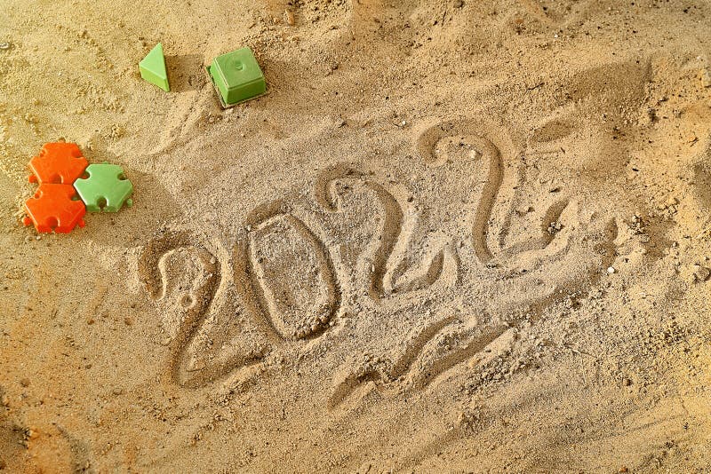 Novo ano 2022 escrito à mão sobre areia úmida na praia por mar ou oceano. contagem regressiva na véspera do feriado foto de stock