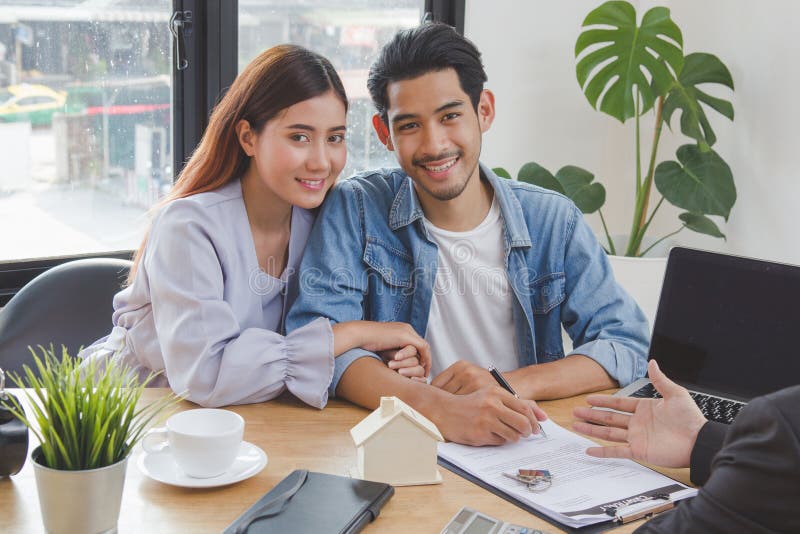 Novo conceito de mudança de casa e deslocalização. feliz casal asiático assinando contrato de compra de apartamento