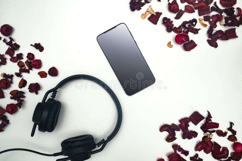 White background with mobile and headphones with dry red leaves scattered on the surface. White background with mobile and headphones with dry red leaves scattered on the surface