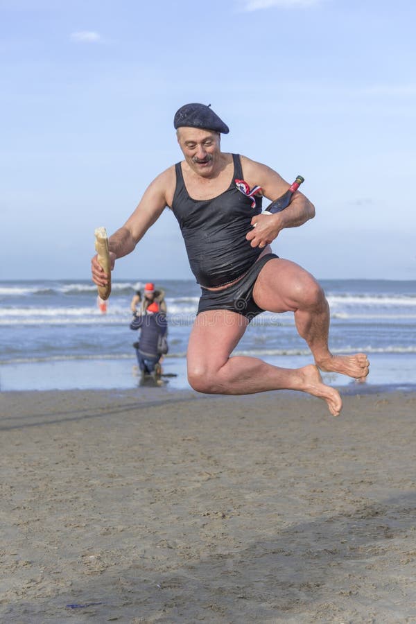 SCHEVENINGEN, 1 January 2018 - Dutch guy disguise with the typical French costume, Super Dupon character, baguette bread, bottle of wine and French berret hat, dancing on the beach. The first new year dive is a one of the oldest Dutch tradition to do at the beginning of the new year all around the Netherlands. SCHEVENINGEN, 1 January 2018 - Dutch guy disguise with the typical French costume, Super Dupon character, baguette bread, bottle of wine and French berret hat, dancing on the beach. The first new year dive is a one of the oldest Dutch tradition to do at the beginning of the new year all around the Netherlands