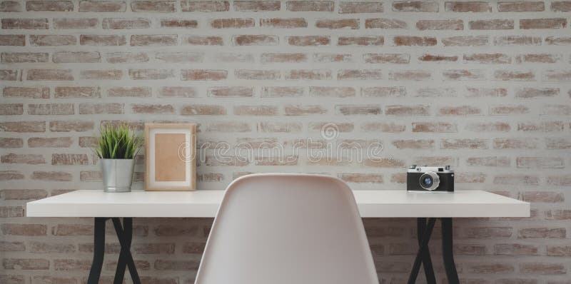 Loft modern workplace with white wooden table with office supplies and copy space with brick wall background. Loft modern workplace with white wooden table with office supplies and copy space with brick wall background