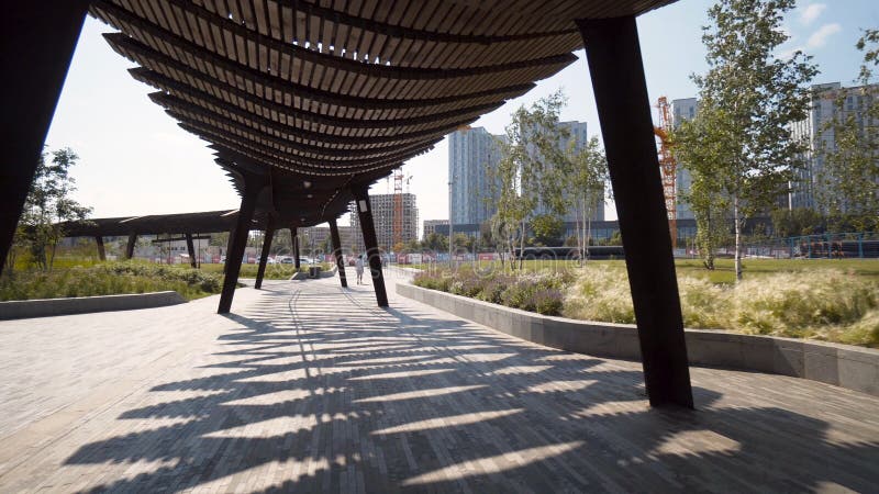 Modern pergolas in park on sunny day. Action. Long pavilions or pergolas in modern city park. Beautiful architectural solutions for recreation areas in park. Modern pergolas in park on sunny day. Action. Long pavilions or pergolas in modern city park. Beautiful architectural solutions for recreation areas in park.