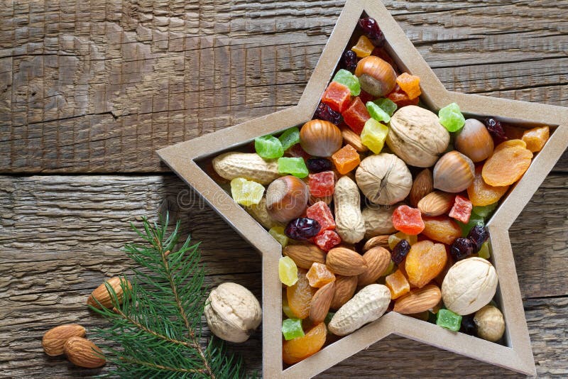 Christmas nuts and dried fruit mix in star-shaped bowl on wooden background assortment of delicacies concept. Christmas nuts and dried fruit mix in star-shaped bowl on wooden background assortment of delicacies concept