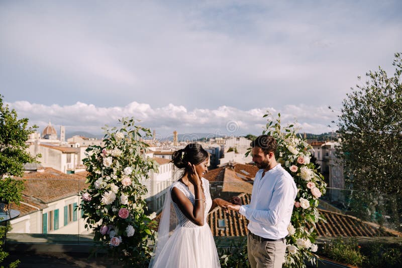 Nozze d'arte di destinazione in florence italia. coppia di matrimoni multirazziali. una cerimonia nuziale sul tetto del