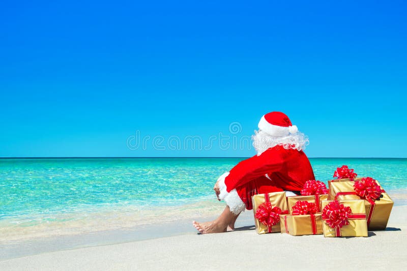 Noël Santa Claus avec des boîte-cadeau détendant à la plage d'océan