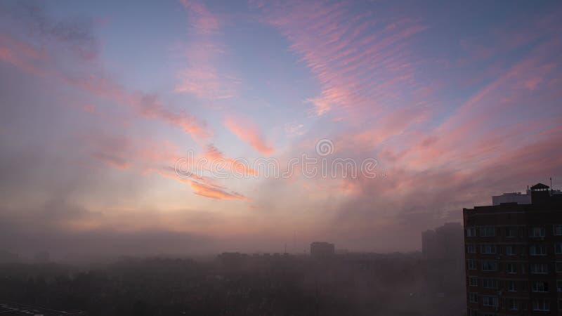 Nublado amanecer rojo sobre la ciudad con nubes fluidas