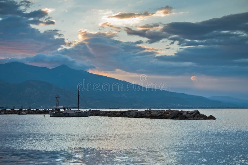 Nuble-se reflexões em uma água do Mar Egeu no nascer do sol, porto de Volos com a montanha de Pelion no fundo foto de stock Nuble-se reflexões em uma água do Mar Egeu no nascer do sol, porto de Volos com a montanha de Pelion no fundo foto de stock