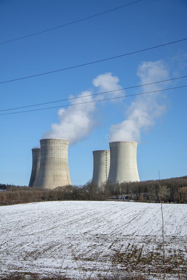 Jadrová elektráreň v zime. Chladiace veže. Modrá obloha v pozadí. Sneh na poľnohospodárskom poli