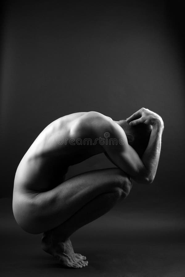 Young muscular nude man over black background stock image.