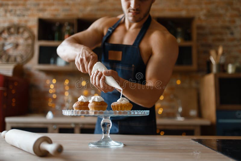 Nude man in apron cooking dessert on the kitchen stock images.