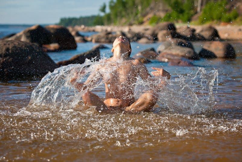 Nude woman sitting in the sea and playing with a water splashes 