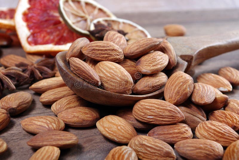 Nueces de almendra en cuchara y frutos secos en una mesa de madera cerca. almendras, estrellas del anÃs y pomelo seco fotografía de archivo libre de regalías Nueces de almendra en cuchara y frutos secos en una mesa de madera cerca. almendras, estrellas del anÃs y pomelo seco fotografía de archivo libre de regalías