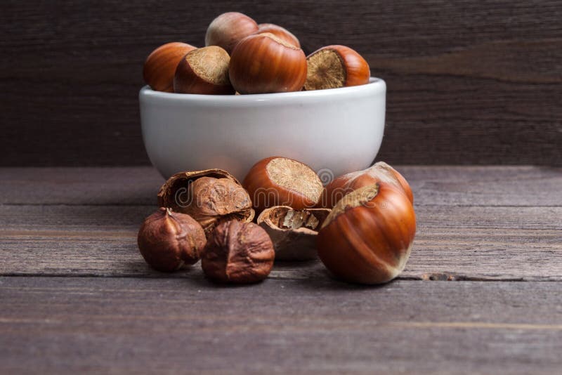 Nueces de la avellana en el cuenco blanco de la porcelana en fondo de madera fotografía de archivo libre de regalías Nueces de la avellana en el cuenco blanco de la porcelana en fondo de madera fotografía de archivo libre de regalías