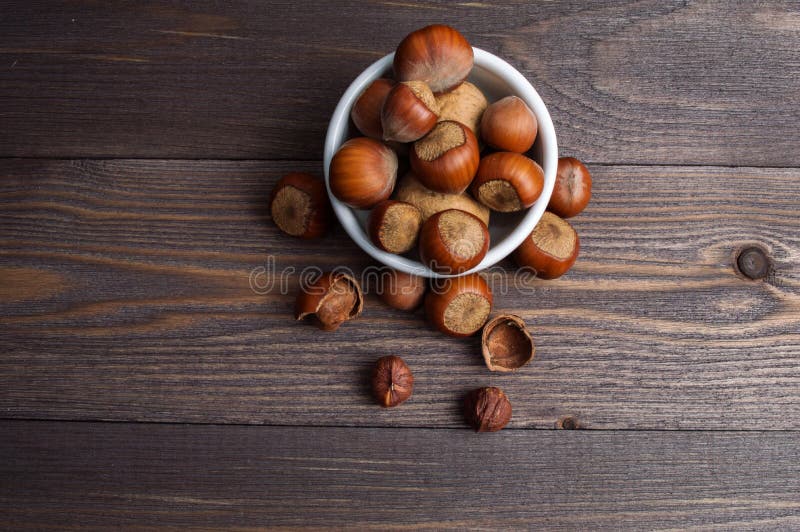 Nueces de la avellana en el cuenco blanco de la porcelana en fondo de madera foto de archivo libre de regalías Nueces de la avellana en el cuenco blanco de la porcelana en fondo de madera foto de archivo libre de regalías