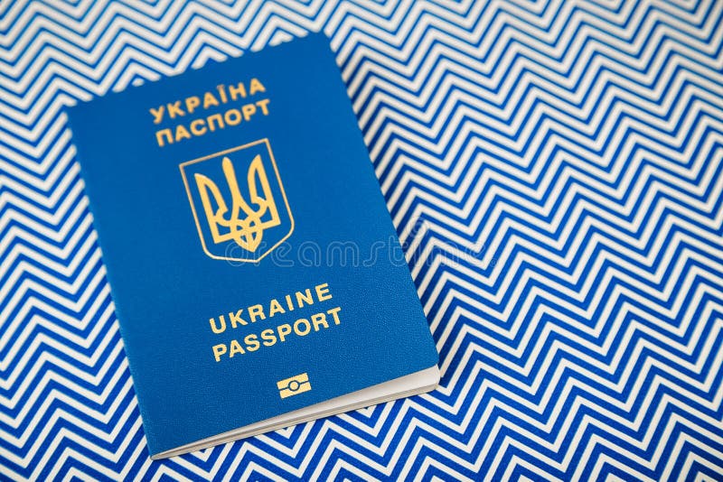 Nuevo pasaporte biométrico internacional azul ucraniano con el microprocesador de la identificación en el fondo blanco y azul con imagen de archivo libre de regalías Nuevo pasaporte biométrico internacional azul ucraniano con el microprocesador de la identificación en el fondo blanco y azul con imagen de archivo libre de regalías