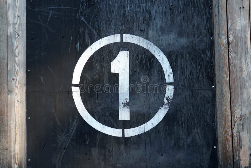 Number 1 in circle, on old rubber banner on stadium wall. White winner stamp with scratches on black background royalty free stock photo