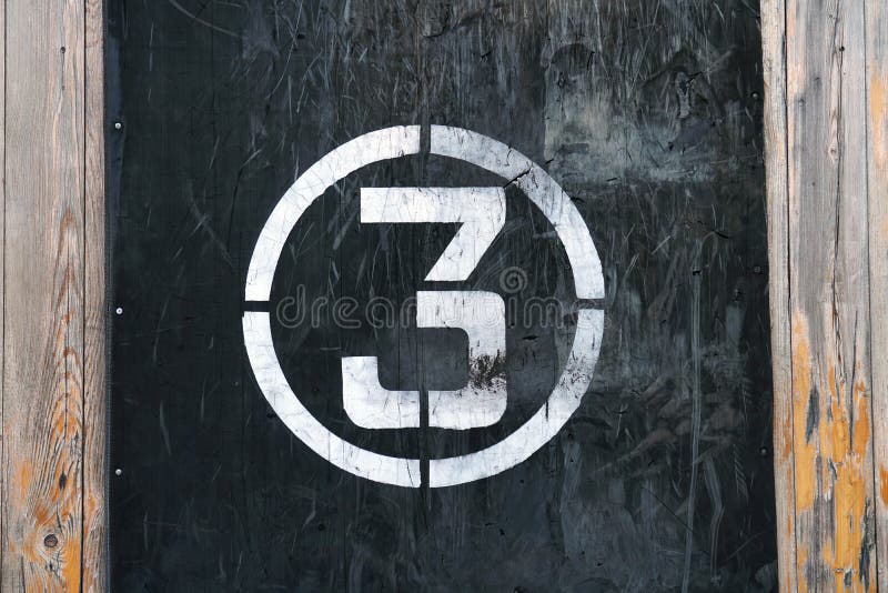 Number 3 in circle, on old rubber banner on stadium wall. White winner stamp with scratches on black background royalty free stock photo