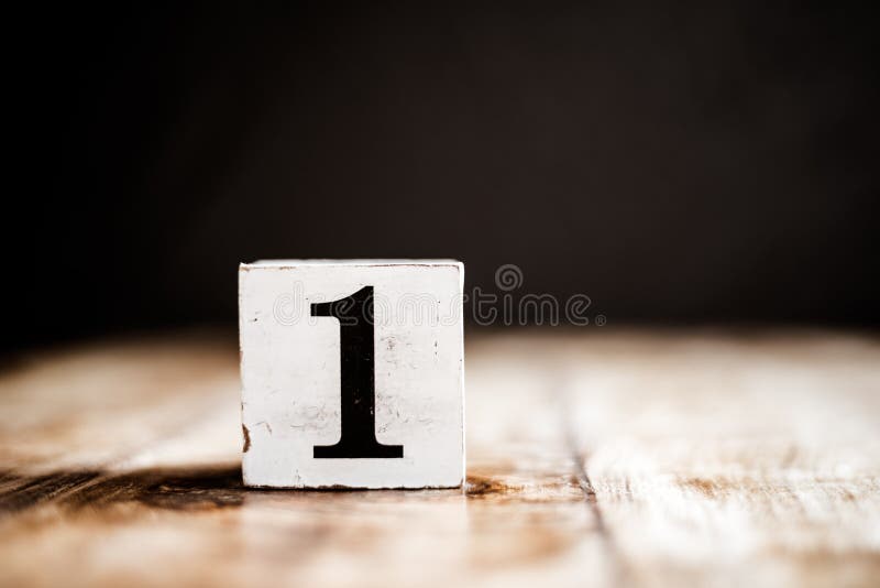 1 - Number 1 - Number One - White block with number on wooden table and dark background