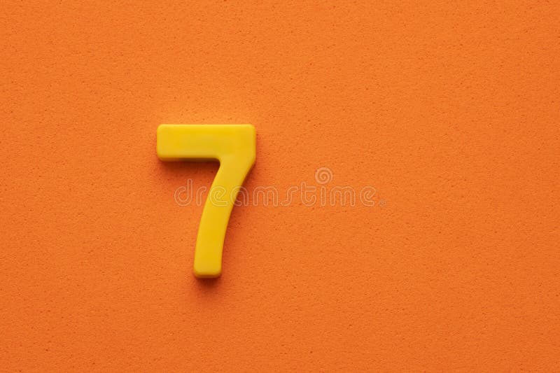 Number Seven Yellow Plastic Plastic Digit on Orange Foamy Background