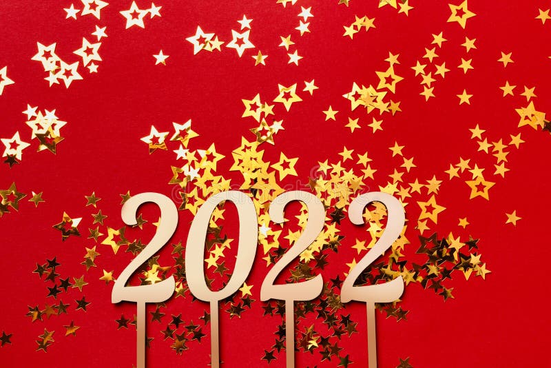 2022 numbers and gold stars confetti on Red sparkling background. Christmas or new year concept