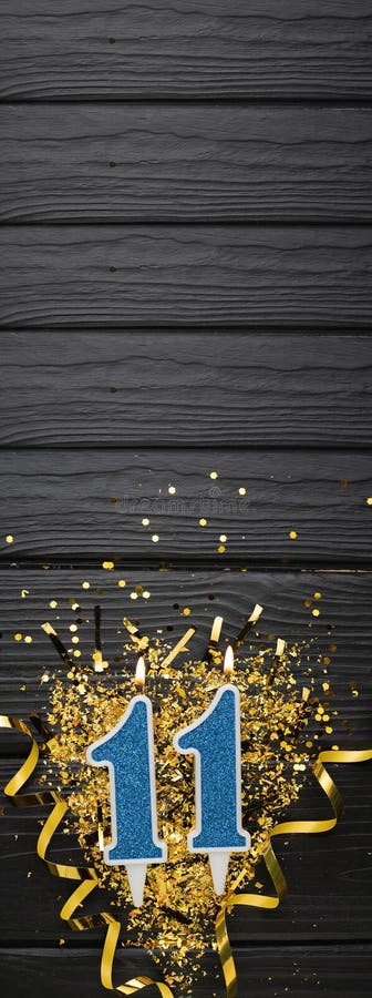 Number 11 blue celebration candle and gold confetti on dark wooden background. 11th birthday card. Anniversary and birthday concept. Vertical banner. Copy space. Number 11 blue celebration candle and gold confetti on dark wooden background. 11th birthday card. Anniversary and birthday concept. Vertical banner. Copy space