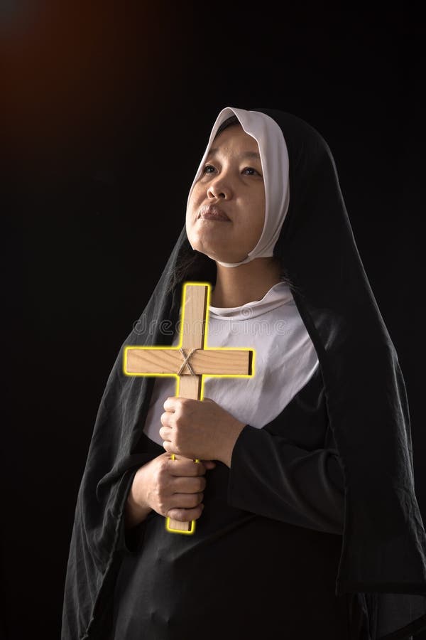 Nuns praying to the GOD while holding a crucifix symbol with golden light in black background. Religious Nun in religion concept; Nuns praying to the GOD while royalty free stock photos Nuns praying to the GOD while holding a crucifix symbol with golden light in black background. Religious Nun in religion concept; Nuns praying to the GOD while royalty free stock photos