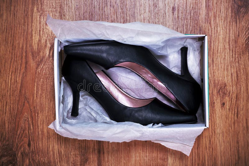 Photo of a pair of new womens court shoes in a shoe box on rustic wooden floor. Photo of a pair of new womens court shoes in a shoe box on rustic wooden floor.
