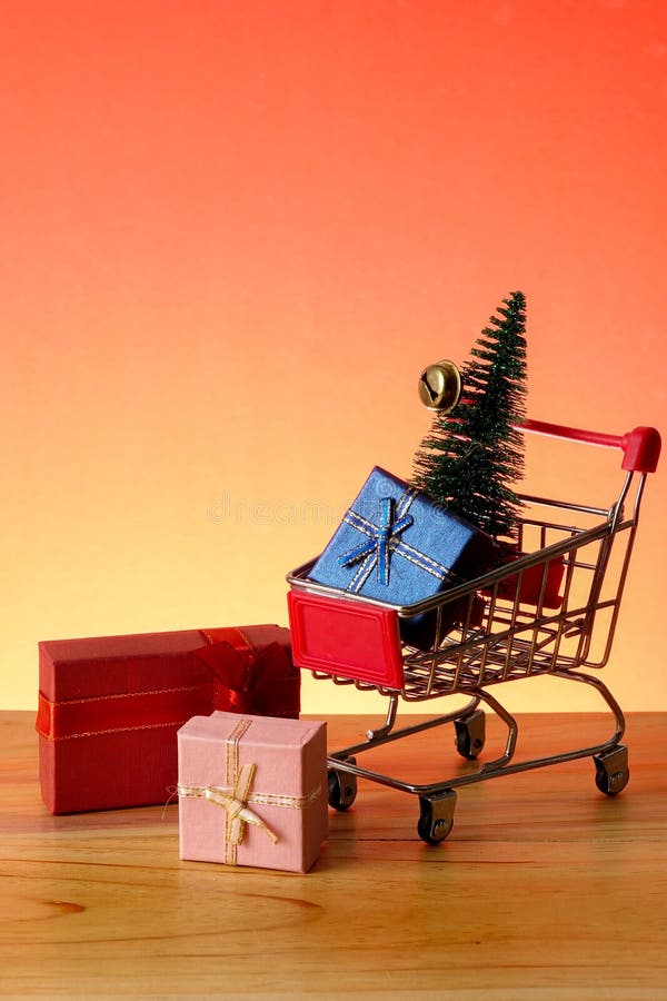 NUOVO ANNO CONCETTUALE con il carrello, i contenitori di regalo e l'albero di Natale di compera su una tavola di legno fotografia stock libera da diritti NUOVO ANNO CONCETTUALE con il carrello, i contenitori di regalo e l'albero di Natale di compera su una tavola di legno fotografia stock libera da diritti