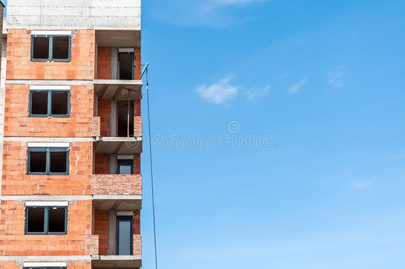 Nuovo cantiere dell'edificio residenziale con le finestre ed il chiaro cielo blu con lo spazio della copia, concetto industriale fotografia stock Nuovo cantiere dell'edificio residenziale con le finestre ed il chiaro cielo blu con lo spazio della copia, concetto industriale fotografia stock