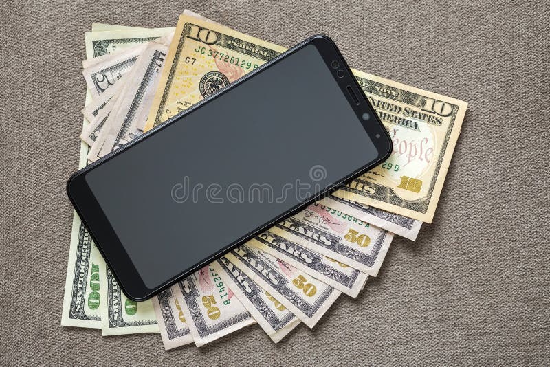 Nuovo cellulare moderno nero sul fondo delle banconote dei dollari dei soldi Tecnologia moderna, comunicazione e commercio online