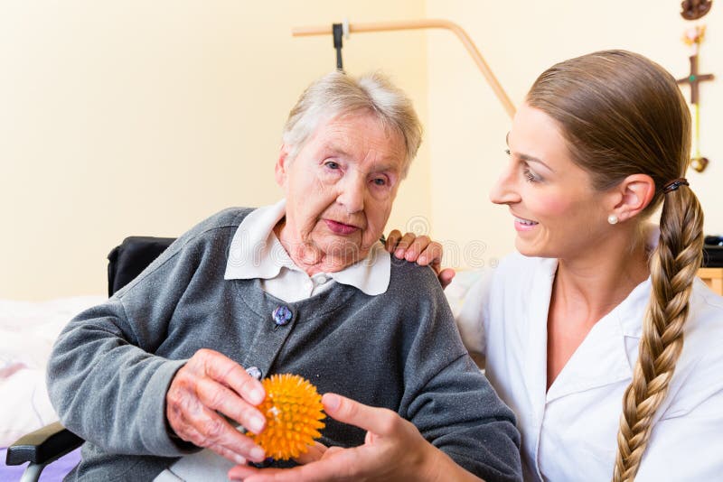 Nurse giving physical therapy with massage ball to senior women in wheelchair. Nurse giving physical therapy with massage ball to senior women in wheelchair