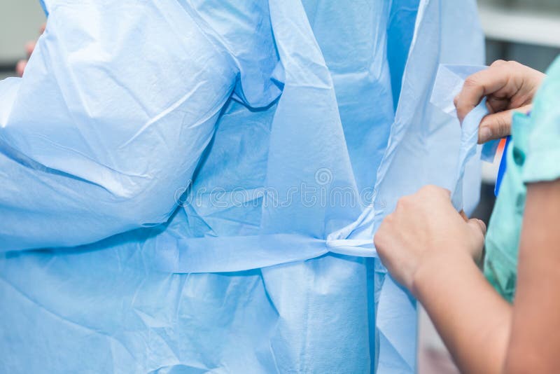 Nurse Helping Doctor Getting Dressed with Disposable Sterile Clothes