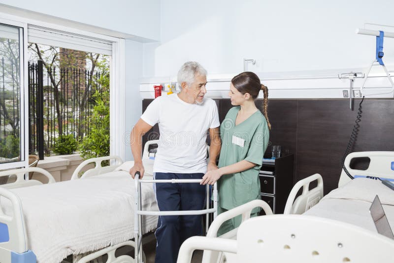 Nurse Helping Male Patient In Using Walker At Nursing Home stock photo Nurse Helping Male Patient In Using Walker At Nursing Home stock photo