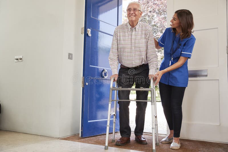 Nurse helping senior man using a walking frame at home