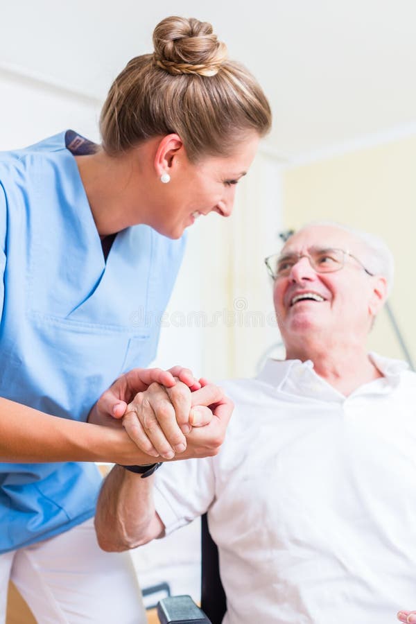 Nurse holding hand of senior men in rest home
