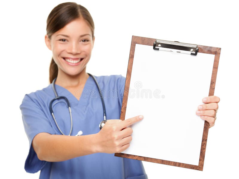 Nurse showing medical sign clipboard copy space. Female medical doctor or nurse pointing at blank empty copyspace. Young mixed race Asian Caucasian woman model in blue scrubs isolated on white.
