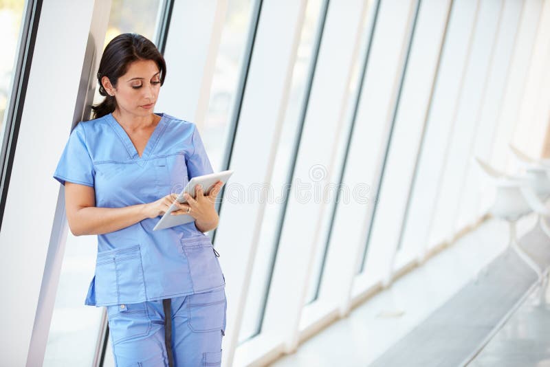 Nurse Using Digital Tablet In Corridor Of Modern Hospital royalty free stock images Nurse Using Digital Tablet In Corridor Of Modern Hospital royalty free stock images
