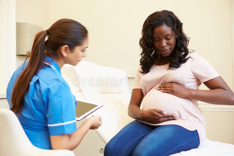 Nurse Using Digital Tablet In Meeting With Pregnant Woman stock photos Nurse Using Digital Tablet In Meeting With Pregnant Woman stock photos