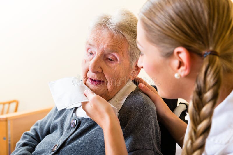 Nurse wiping mouth of elderly senior women in nursing home. Nurse wiping mouth of elderly senior women in nursing home