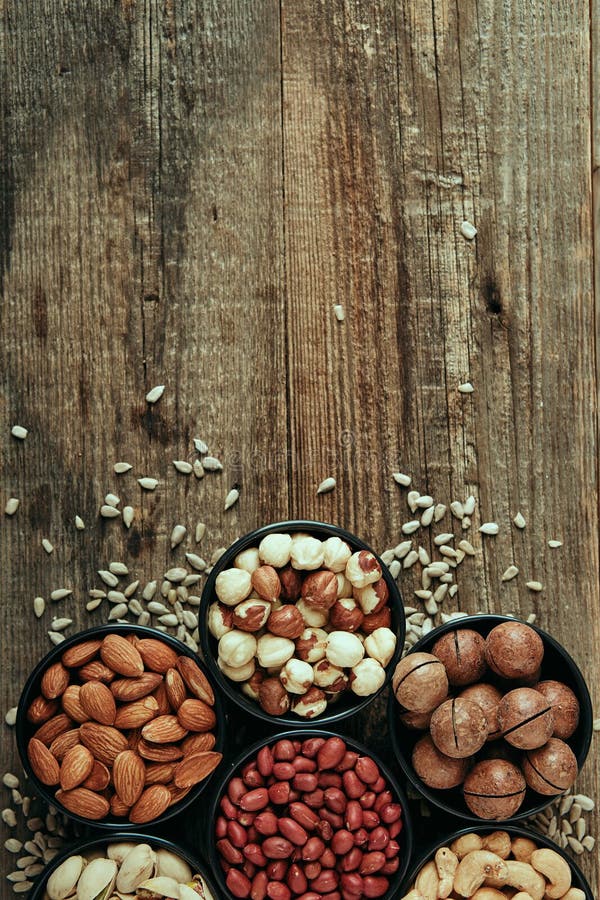 Nut mix of cashews, pistachios, almonds, macadamia, walnuts and sunflower seeds in bowls on wooden table. High quality photo