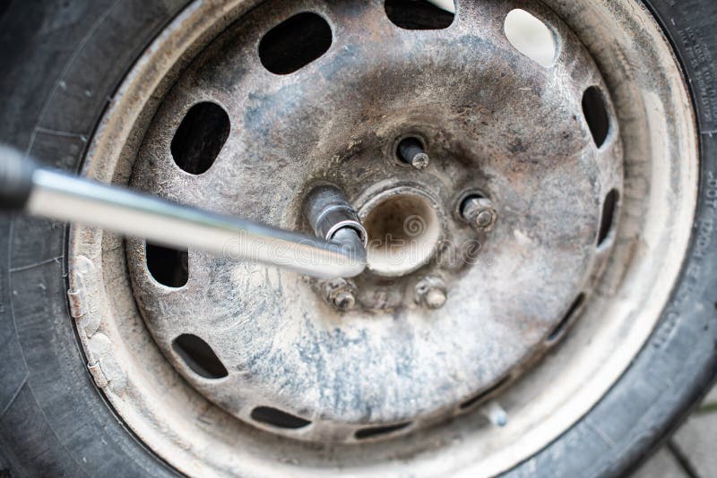 The nut of the used car wheel is screwed out with a wrench royalty free stock photos