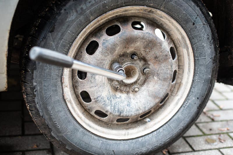 The nut of the used car wheel is screwed out with a wrench royalty free stock photography