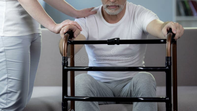 Nutra o pensionista masculino de apoio que guarda o quadro de passeio, centro de reabilitação foto de stock royalty free Nutra o pensionista masculino de apoio que guarda o quadro de passeio, centro de reabilitação foto de stock royalty free