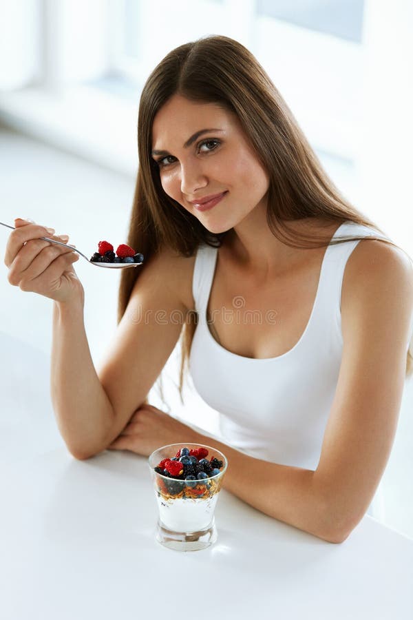 Nutrição da dieta saudável Iogurte, bagas e cereal comer da mulher foto de stock Nutrição da dieta saudável Iogurte, bagas e cereal comer da mulher foto de stock