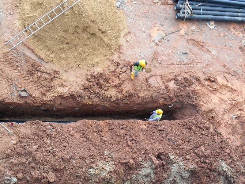 KUALA LUMPUR, MALAYSIA -MARCH 25, 2017: Trenches excavated at the construction site by construction workers to accommodate the utility services. KUALA LUMPUR, MALAYSIA -MARCH 25, 2017: Trenches excavated at the construction site by construction workers to accommodate the utility services.