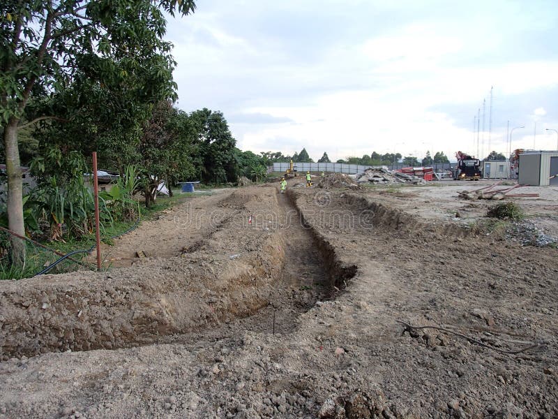 KUALA LUMPUR, MALAYSIA -MARCH 25, 2017: Trenches excavated at the construction site by construction workers to accommodate the utility services. KUALA LUMPUR, MALAYSIA -MARCH 25, 2017: Trenches excavated at the construction site by construction workers to accommodate the utility services.