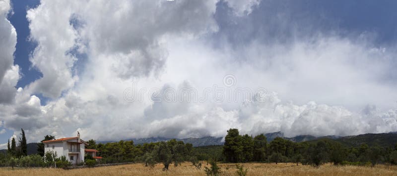 Nuvens de cúmulo gigantes antes da tempestade de aproximação do verão em uma vila na ilha grega de Evia imagem de stock Nuvens de cúmulo gigantes antes da tempestade de aproximação do verão em uma vila na ilha grega de Evia imagem de stock
