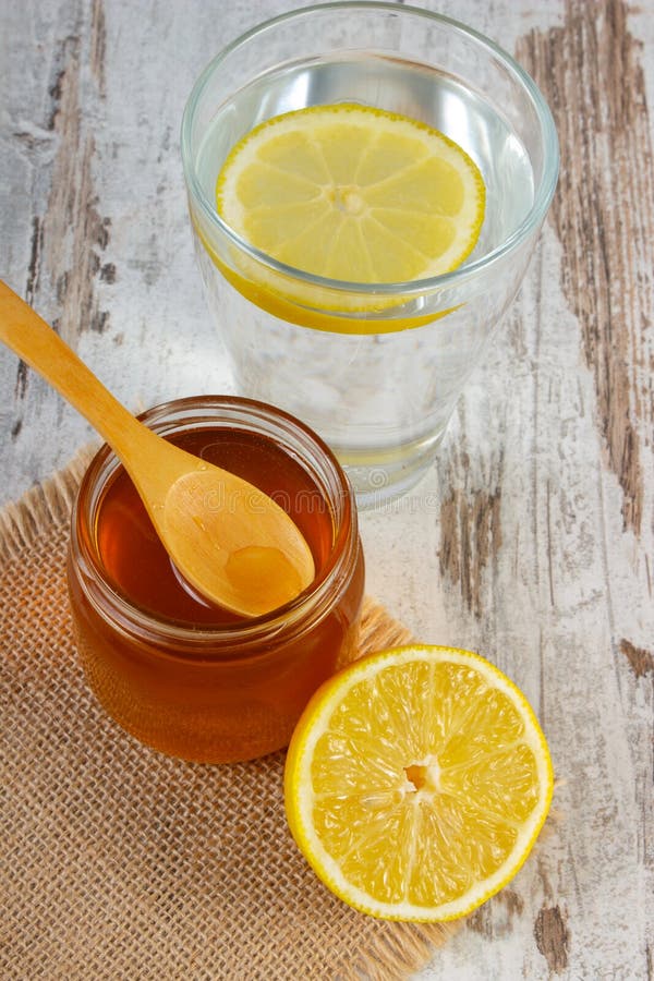 Ny citron med honung och exponeringsglas av vatten med skivan av citronen fotografering för bildbyråer Ny citron med honung och exponeringsglas av vatten med skivan av citronen fotografering för bildbyråer