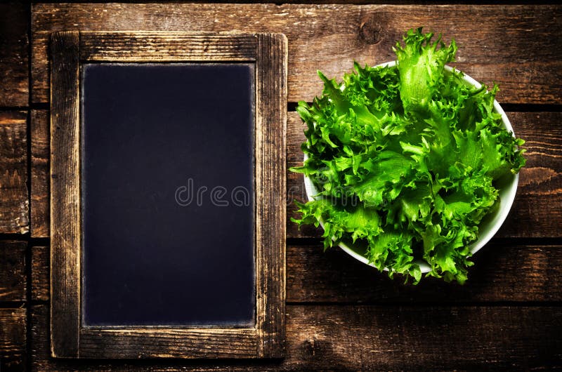Fresh green Lettuce Salad on blank vintage slate chalk board on wooden table. Fresh green Lettuce Salad on blank vintage slate chalk board on wooden table
