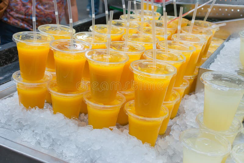 Ny orange fruktsaft i plast- exponeringsglas på en säng av is royaltyfri fotografi Ny orange fruktsaft i plast- exponeringsglas på en säng av is royaltyfri fotografi